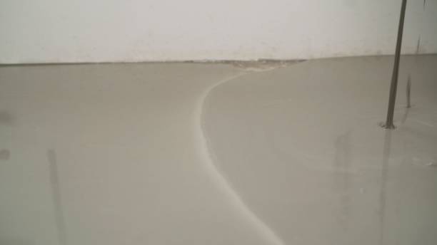istock Workers level the floor with mortar. Self-priming liquid floor. Adjust the mixed cement in the mold. Floor repair. 1319828881