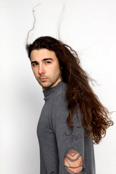 istock Attractive young guy with very long curly hair is posing in studio. 1319828941