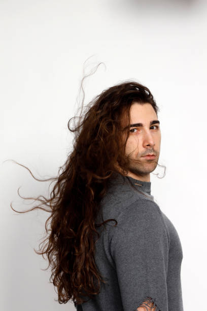 istock Attractive young guy with very long curly hair is posing in studio. 1319828942
