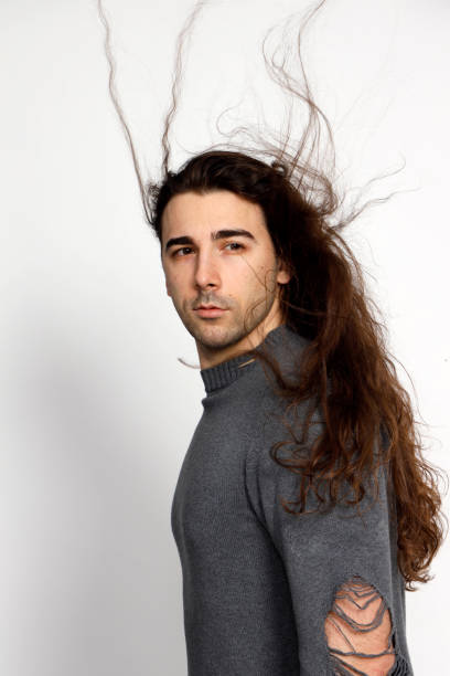 istock Attractive young guy with very long curly hair is posing in studio. 1319828963
