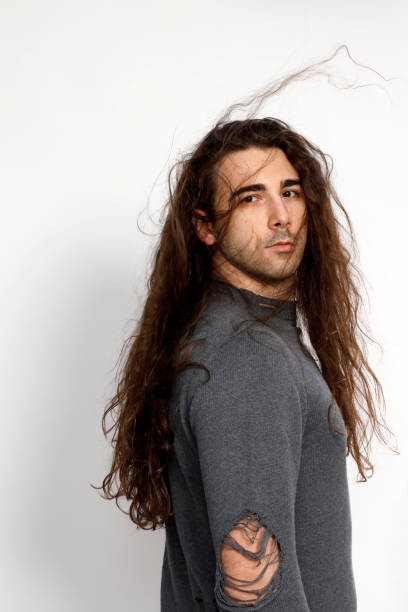 istock Attractive young guy with very long curly hair is posing in studio. 1319828987