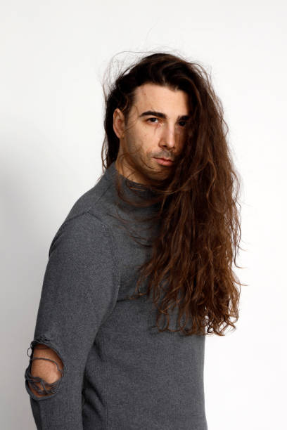 istock Attractive young guy with very long curly hair is posing in studio. 1319829009
