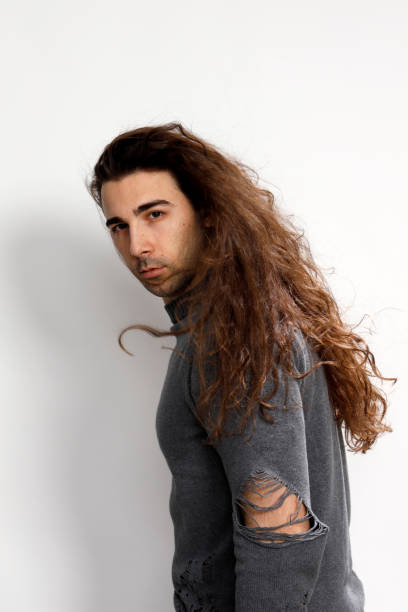 istock Attractive young guy with very long curly hair is posing in studio. 1319829029