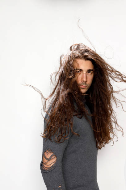 istock Attractive young guy with very long curly hair is posing in studio. 1319829058
