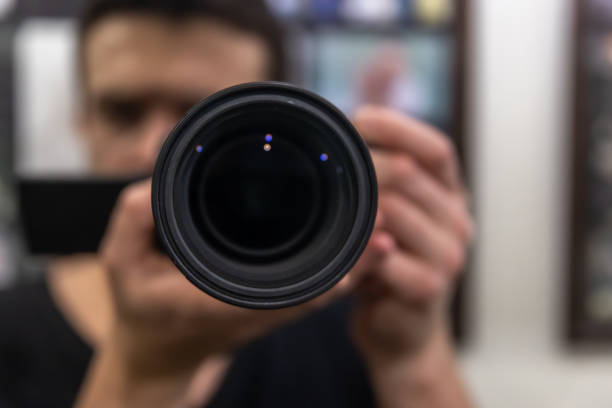 istock Close-up lens in the hands of a man on a blurred background. 1319829850