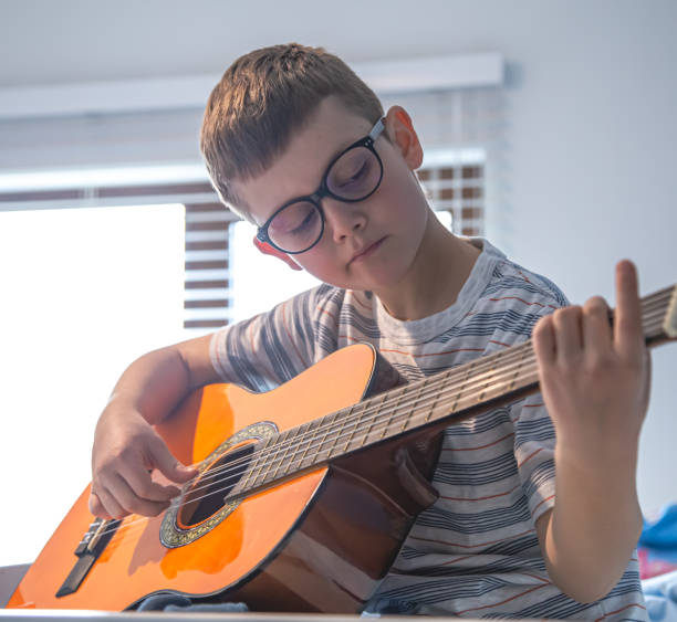 istock Little boy learning to play the classical guitar. 1319830427