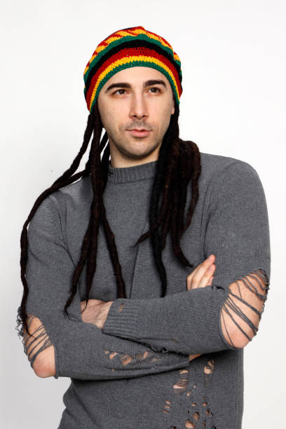 istock Attractive young guy with very long dreadlocks and a cap is posing in studio. 1319832081
