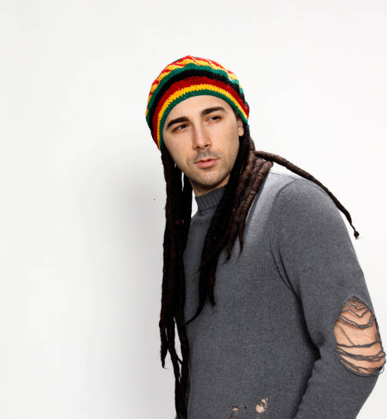 istock Attractive young guy with very long dreadlocks and a cap is posing in studio. 1319832114