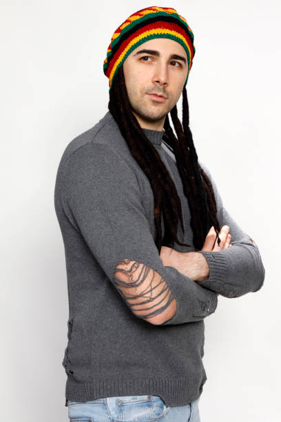 istock Attractive young guy with very long dreadlocks and a cap is posing in studio. 1319832154