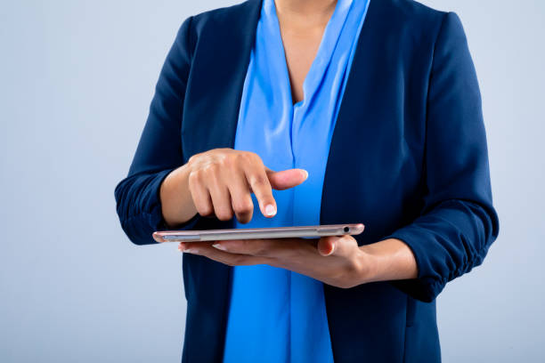 istock Mid section of businesswoman using a digital tablet against grey background 1319834652