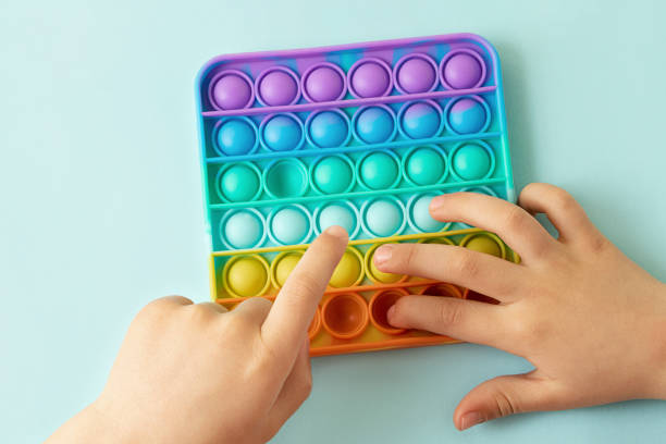 istock Child playing with rainbow pop it,pressing the bubbles with his fingers,top view.New antistress toy for children and adult.Copy space for text or design. 1319834919