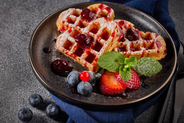 istock Delicious waffles heart shape with  powdered sugar and berries on  plate on grey background. Top view.  Sweet meal. Dessert 1319835190