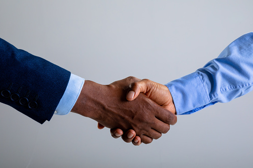 Mid section of two businessman shaking hands against grey background. business agreement and professionalism concept