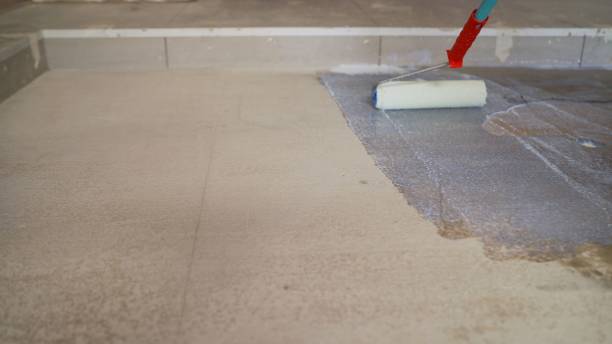 istock Concrete floor priming is the final preparatory stage for surface strengthening. Priming the concrete floor with a long handle roller. Floor priming process. 1319836136