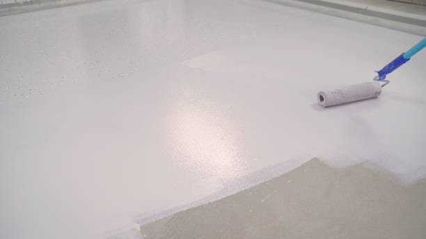 istock A worker paints the concrete floor with a roller white. Concrete Floor repair work. Paint roller in construction site 1319836285