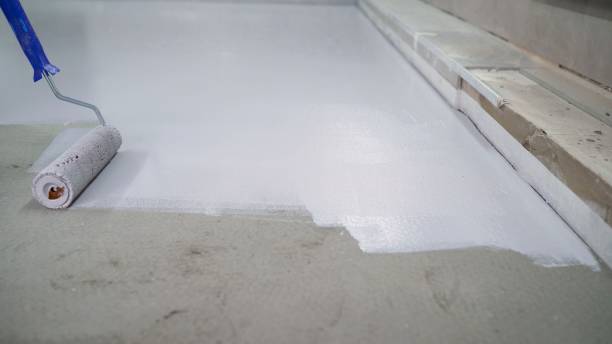 istock A worker paints the concrete floor with a roller white. Concrete Floor repair work. Paint roller in construction site 1319836295