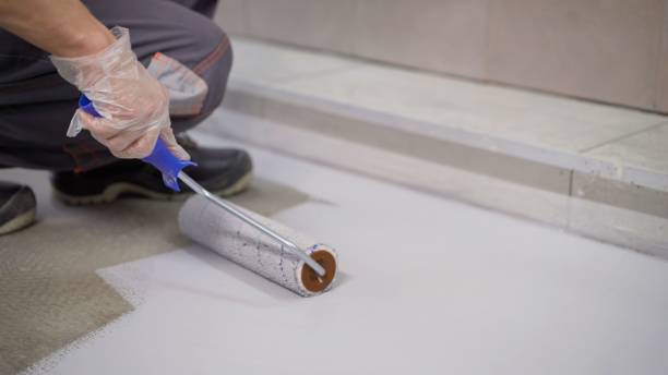 istock A worker paints the concrete floor with a roller white. Concrete Floor repair work. Paint roller in construction site 1319836424