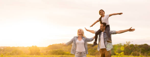 joven familia feliz en un campo - contento fotografías e imágenes de stock