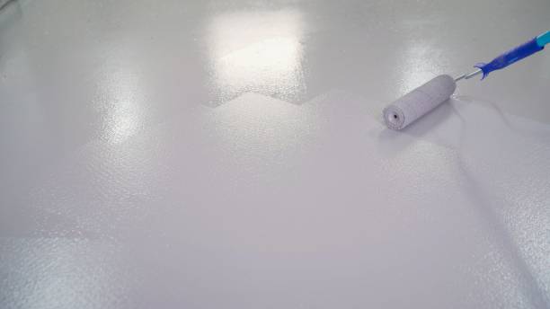 istock Man painting the floor. The floor is painted white with a roller. Blue paint roller, on white background 1319836606