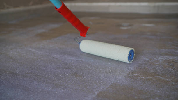 작업자는 롤러가 있는 콘크리트 바닥에 프라이머를 적용합니다. 바닥에 프라이머를 적용합니다. 바닥 프라이밍. 돌의 작업자 브러시 프라이머 그라우트 - priming paint 뉴스 사진 이미지