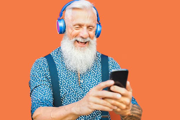 istock Senior man using mobile smartphone while listening music playlist with wireless headphones - Mature hipster male having fun with technology outdoor - Elderly people lifestyle and tech concept 1319836790