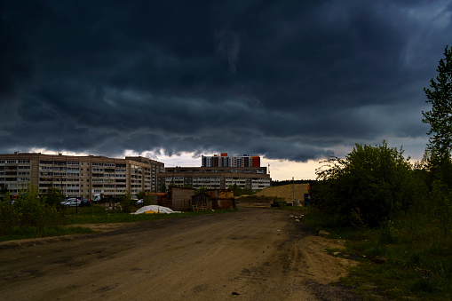 Formidable storm clouds enveloped the outskirts of the city in darkness in the spring before a heavy downpour with lightning and thunder