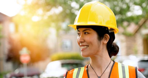 istock Smiling asian female construction worker wearing a work helmet looking away 1319838142
