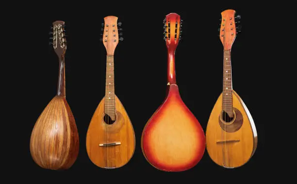 Four different old mandolins isolated on black background.