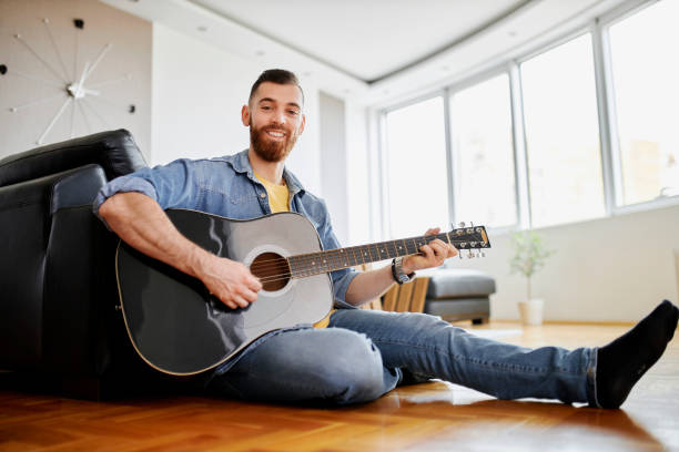 istock Guitarist playing acoustic guitar at home 1319840700