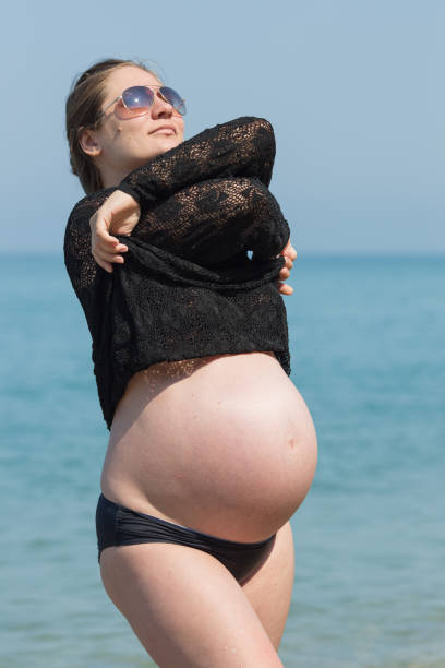 istock Expectant mother in black mesh blouse resting at the sea 1319841413