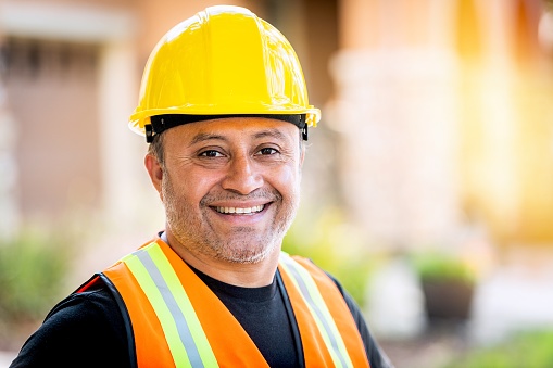 Mug shot of a Smiling hispanic construction worker wearing a work helmet looking at the camera