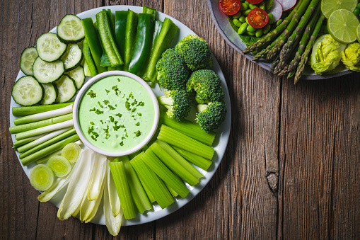 Vegan dip with celery sticks, green pepper, cucumber, fresh garlic, broccoli, endives vegan food Mediterranean diet on wooden rustic table