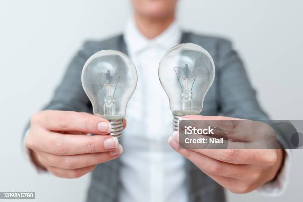 Lady Carrying Two Lightbulbs In Hands With Formal Outfit Presenting Another Ideas For Project Business Woman Holding 2 Lamps Showing Late Technologies Lighbulb Exhibiting Fresh Openion Stock Photo - Download Image Now