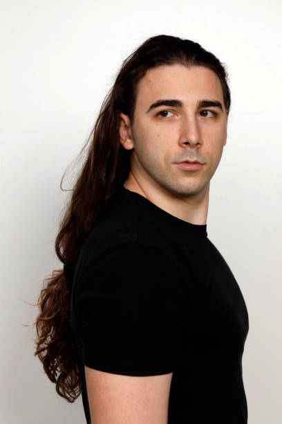 istock Attractive young guy with very long curly hair is posing in studio. 1319846105