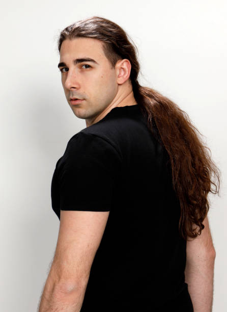 istock Attractive young guy with very long curly hair is posing in studio. 1319846135