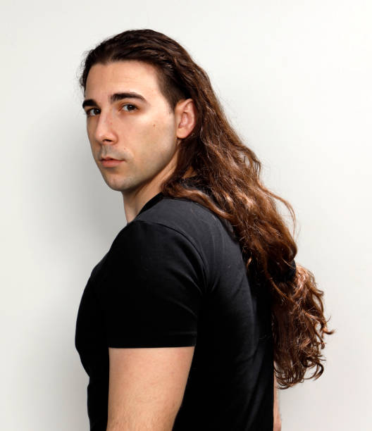 istock Attractive young guy with very long curly hair is posing in studio. 1319846157
