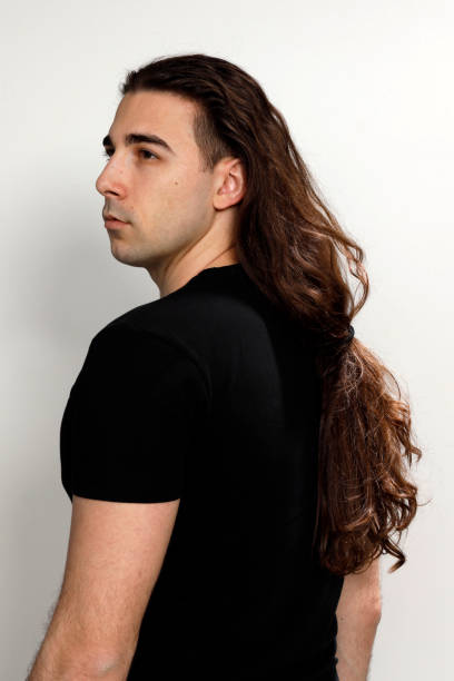 istock Attractive young guy with very long curly hair is posing in studio. 1319846169