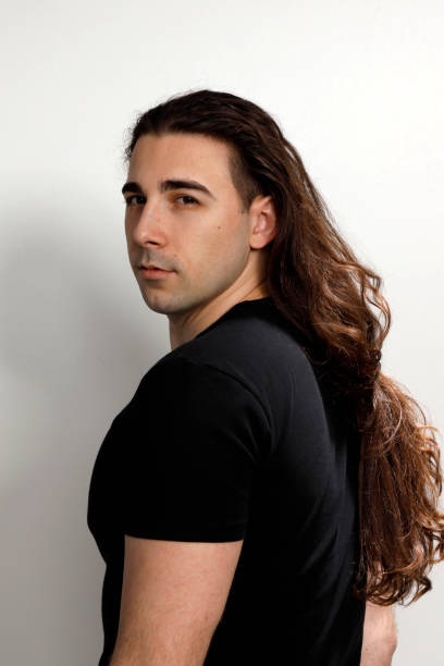 istock Attractive young guy with very long curly hair is posing in studio. 1319846174