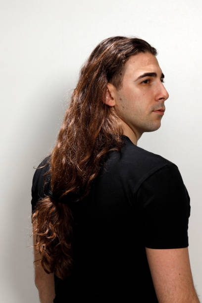 istock Attractive young guy with very long curly hair is posing in studio. 1319846217