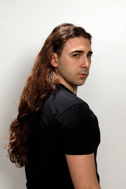istock Attractive young guy with very long curly hair is posing in studio. 1319846250