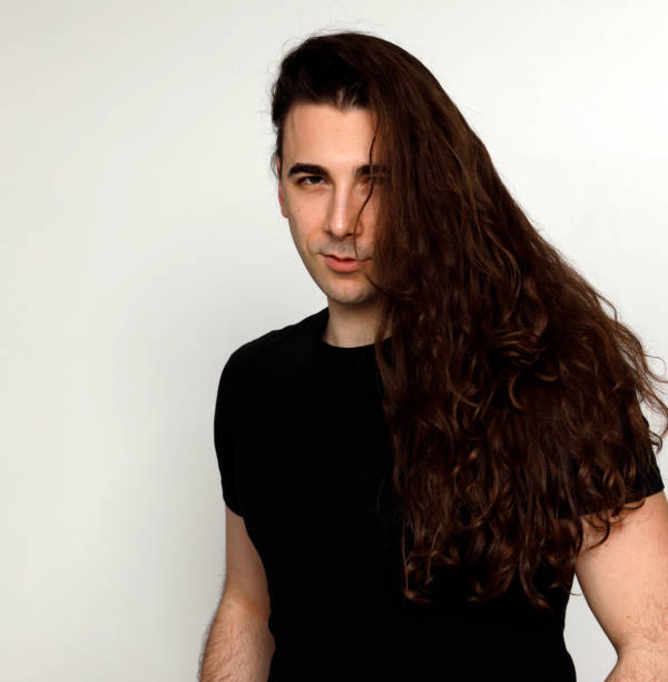 istock Attractive young guy with very long curly hair is posing in studio. 1319846305