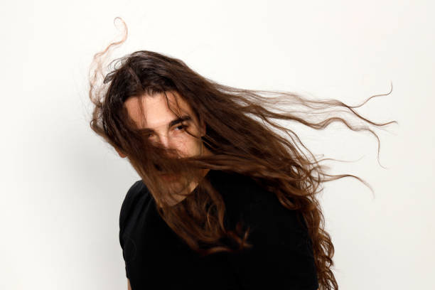 istock Attractive young guy with very long curly hair is posing in studio. 1319846354