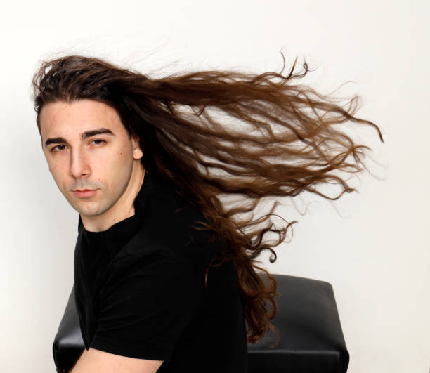 istock Attractive young guy with very long curly hair is posing in studio. 1319846384