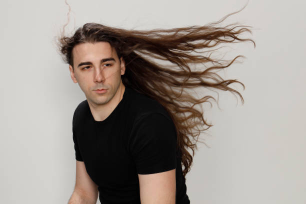 istock Attractive young guy with very long curly hair is posing in studio. 1319846394