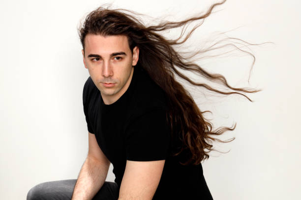 istock Attractive young guy with very long curly hair is posing in studio. 1319846397