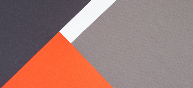Creative abstract geometric paper background orange, white, light gray, black colors paper. Top view