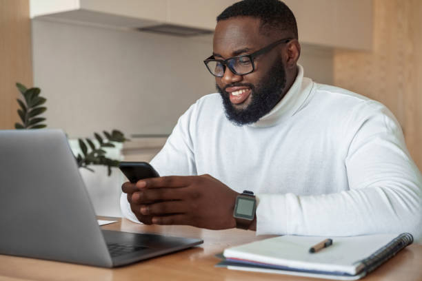 istock Young smiling african american man relaxing using laptop and mobile phone 1319848820