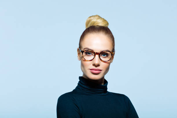 Headshot of confident elegant woman Confident woman wearing black turtleneck and eyeglasses looking at camera. Studio shot on blue background. turtleneck photos stock pictures, royalty-free photos & images