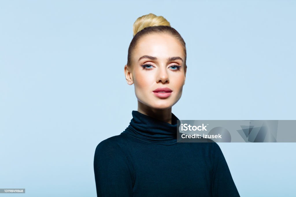 Headshot of confident elegant woman Confident woman wearing black turtleneck looking at camera. Studio shot on blue background. Turtleneck Stock Photo
