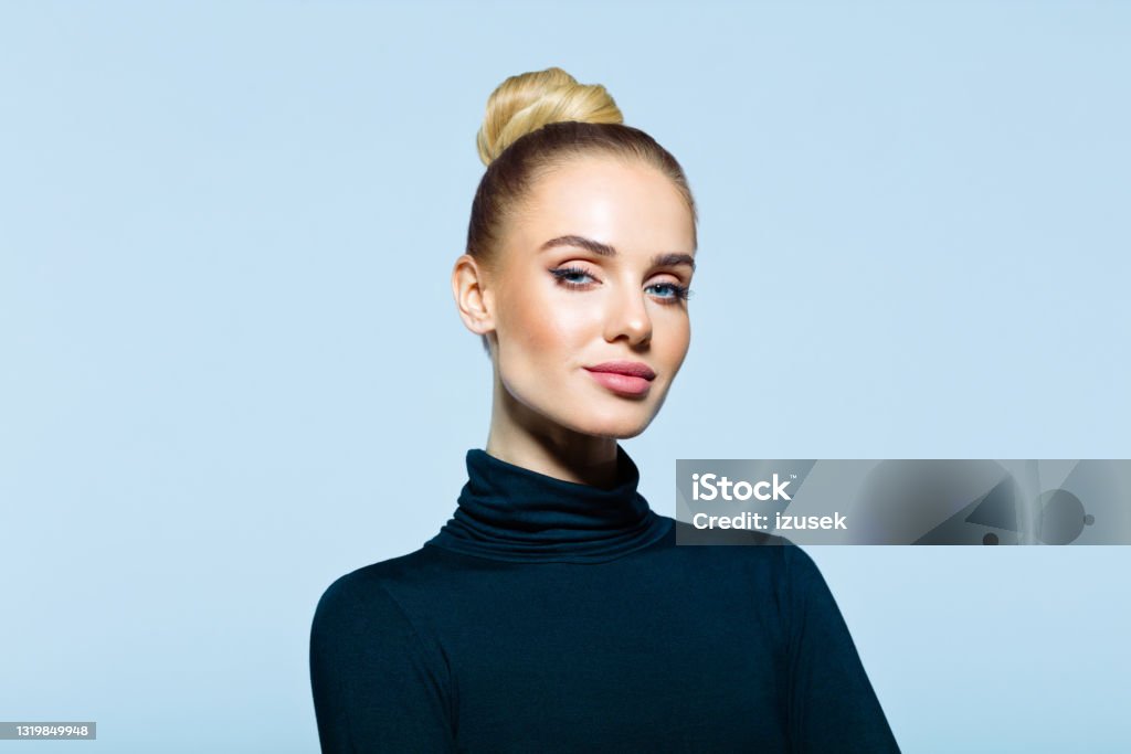 Headshot of confident elegant woman Confident woman wearing black turtleneck looking at camera. Studio shot on blue background. Women Stock Photo